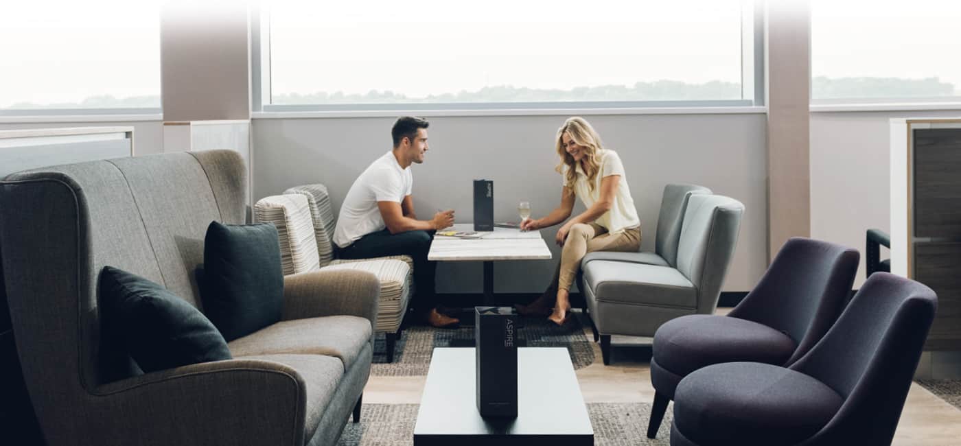 Two people sitting together in an airport lounge with glasses of champagne.