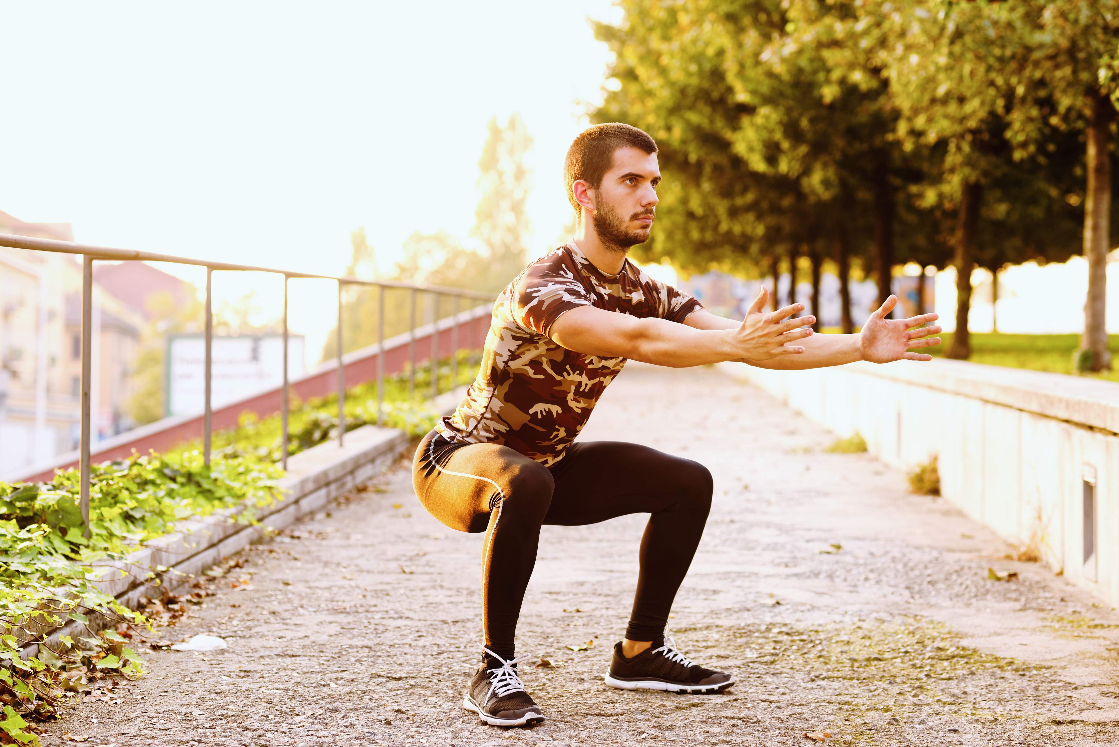 Image of a man squatting outdoors.