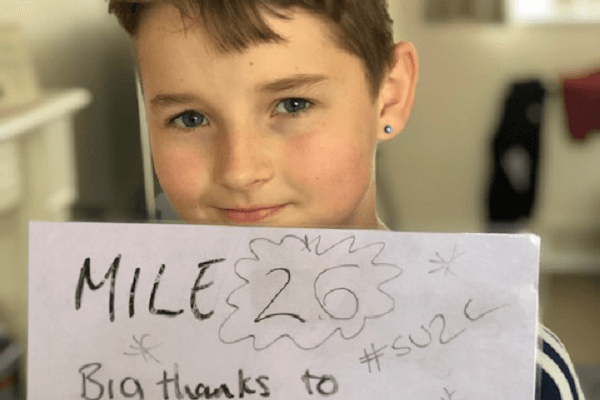 Boy holding a sign that reads 'Mile 26. Big thanks to #SU2C'.