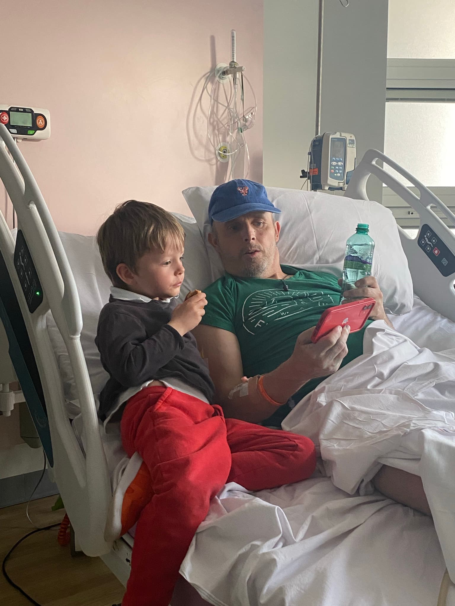 Image of Hughie with his son in a hospital bed.