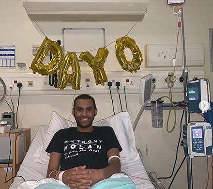 Cameron sat smiling in a hospital bed with day zero written in balloons above him.