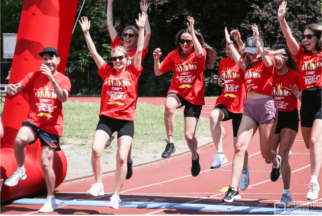 A group of people doing the sprintathon running over the finish line.