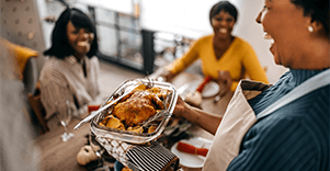 Three black women smiling over a roast chicken, fresh from the oven.